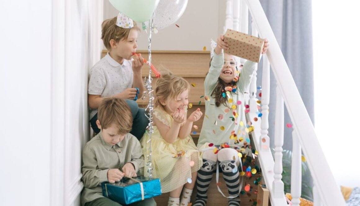 Children enjoying a lively birthday party with balloons, gifts, and confetti on a staircase.